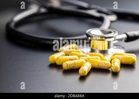 Vitaminkapseln. Vitamin-C-Pillen und Stethoskop auf schwarzem Hintergrund. Stockfoto