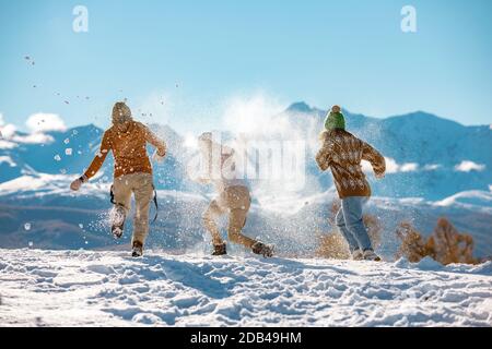 Drei junge glückliche Mädchen Freunde haben Spaß im Schneekampf in den Bergen. Erstes Schnee- und Winterurlaubs-Konzept Stockfoto