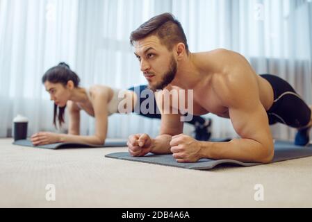 Morgendliches Fitness-Workout des Familienpaares zu Hause. Aktive Mann und Frau in Sportbekleidung tun Push-up-Übung in ihrem Haus, gesunder Lebensstil, Physica Stockfoto