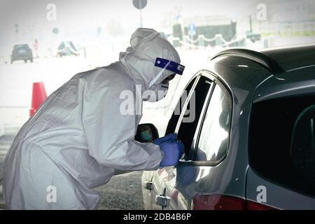 Medizinisches Personal in PSA, das Nasen- und Rachenabstrich an Person im Fahrzeug durch Autofenster durchführt, mobiles Testzentrum COVID-19. Turin, Italien - 2. November Stockfoto