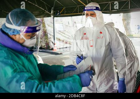 Medizinisches Personal in PSA, das Nasen- und Rachenabstrich an Person im Fahrzeug durch Autofenster durchführt, mobiles Testzentrum COVID-19. Turin, Italien - 2. November Stockfoto