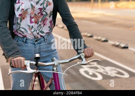 Detail der Hände einer unerkennbaren jungen Frau in der Stadt auf einem Retro-Fahrrad am Radweg, Konzept des aktiven Lebensstils und nachhaltig Stockfoto