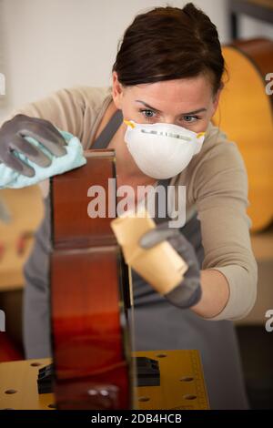 Zimmermannin, die in der Werkstatt einen Gitarrenhals in Holz schleift Stockfoto