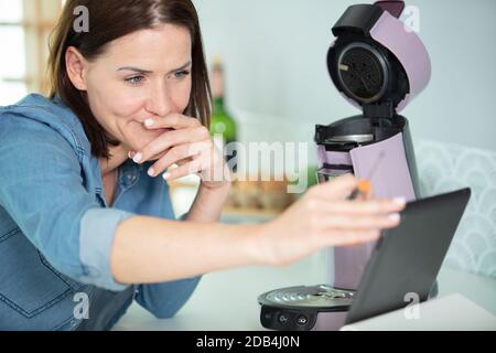 Frau prüft, wie man eine Kaffeemaschine repariert Stockfoto