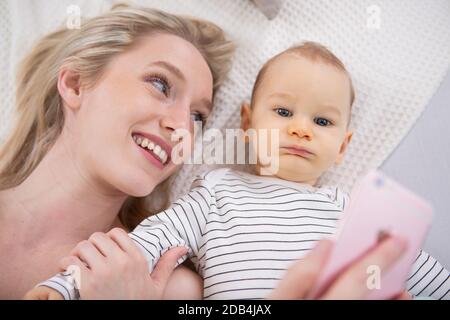 Frau mit einem Baby, das ein Selfie lügt Stockfoto