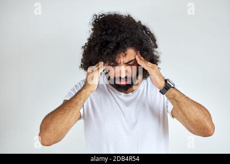 Trauriger arabischer Mann hat Probleme, er ist deprimiert, hält Hand am Kopf, steht in Gedanken, isoliert auf weißem Hintergrund Stockfoto