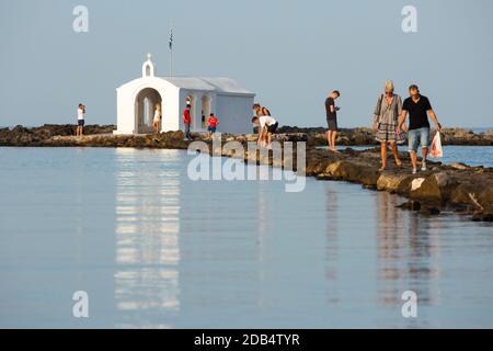 Touristen überqueren den felsigen Weg zur Agios Nikolaos Kapelle im Dorf Georgioupoli, Kreta, Griechenland Stockfoto
