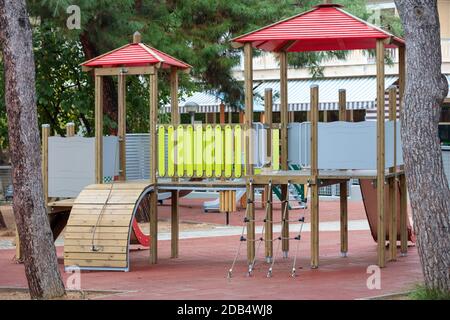 Moderner Spielplatz mit bunten Holzrutschen und Leitern in der Nähe von Baumstämmen. Unterhaltung für Kinder Stockfoto