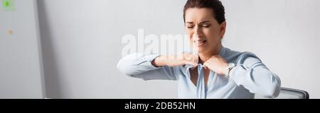 Wütend Brünette Geschäftsfrau mit schmerzenden Hals entbinden Bluse auf verschwommenem Hintergrund, Banner Stockfoto