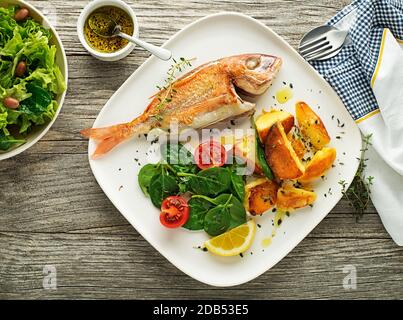 Köstliches gegrilltes Fischfleisch mit Spinat und Kartoffeln im Vintage-Hintergrund. Gesunde Ernährung Stockfoto