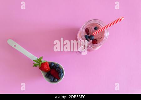 Draufsicht auf Erdbeere und Waldbeeren Smoothie, auf rosa Hintergrund.natürliche Früchte Saft, gesunde Detox Essen und Trinken Konzept. Stockfoto