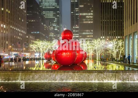 Riesige Weihnachtsschmuck auf einem Brunnen in Manhattan bei Nacht. Große Bälle und helle Lichter Dekoration in 6th Avenue. Wolkenkratzer im Hintergrund. Stockfoto