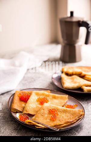 Traditionelle russische Pfannkuchen mit rotem Kaviar. Gebratene Crepes mit Kaviar und saurer Sahne Stockfoto