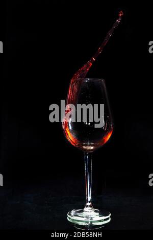 Rotwein spritzt in dunklem Hintergrund aus dem Glas Stockfoto