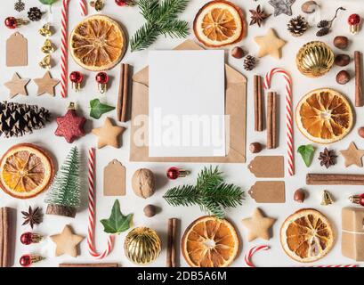 Mehrfarbige Weihnachtsknollung und offener Umschlag mit leerer Postkarte für Text auf hellem texturierten Hintergrund. Flach liegend. Draufsicht Stockfoto