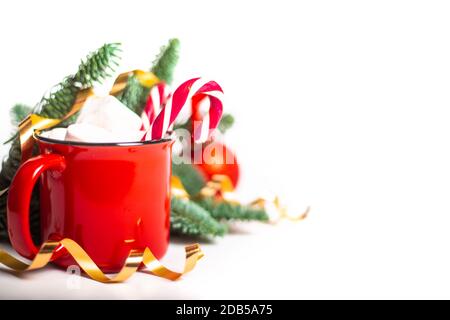 Kakao in rotem Becher mit Marshmallows und Zuckerrohr und Tannenzweige und rote und goldene Kugeln und Sterne Isoliert auf weißem Hintergrund Stockfoto
