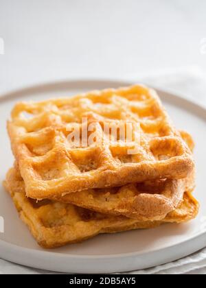 Perfekte herzhafte Keto Waffeln. Zwei Zutaten schabeln auf Teller auf weißem Marmorgrund. Eier und Parmesan-Käse kohlenhydratarme Waffeln. Extrem nah Stockfoto