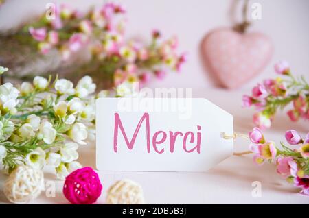 Label Mit Französischem Text Merci Bedeutet Vielen Dank. Rose Und Weiße Blumen Mit Herzschmuck. Stockfoto