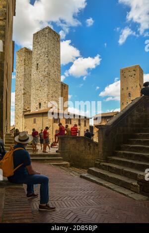 Touristen in Piazza Duomo mit Torri dei Savucci Zwillingstürme, Torre Pettini und Torre Chigi in der mittelalterlichen Stadt San Gimignano, Toskana, Italien Stockfoto