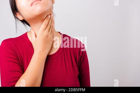 Die schöne asiatische Frau, die ihr den juckenden Hals auf weißem Hintergrund mit Copy-Space, Medical and Healthcare Concept kratzt Stockfoto