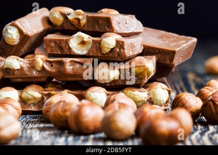 Ganze Haselnüsse im Schokoriegel, die Fliese ist gebrochen und liegt auf dem Holztisch Stockfoto