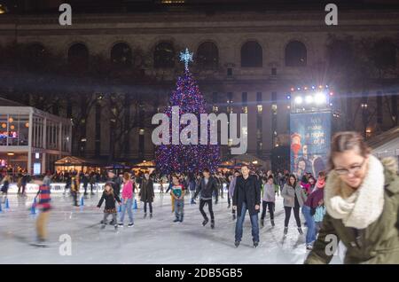 Menschen Schlittschuhlauf auf der Eisbahn im Bryant Park in Manhattan am Weihnachtstag. Beeindruckender Weihnachtsbaum im Hintergrund. New York City, USA Stockfoto