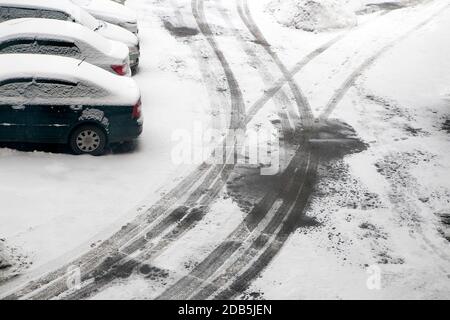 Erster Schnee. Spuren von vorbeifahrenden Autos auf dem Asphalt. Der Winter kommt Stockfoto