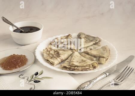 Festliches Gericht für den traditionellen russischen Urlaub Maslenitsa-Pfannkuchen mit rotem Kaviar, Marmelade auf dem Tisch. Kopierbereich Stockfoto