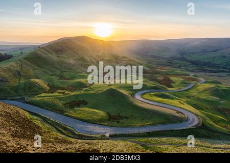 Sonnenuntergang am Mam Tor im Peak District mit einer langen, kurvenreichen Straße durch das Tal. Stockfoto
