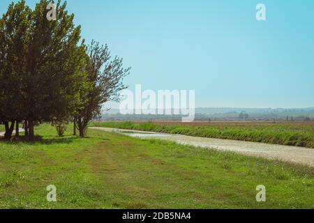 Ländliche Landschaft im Hula-Tal in Israel an einem Sommertag. Ein fließender Fluss mit Gras an den Ufern und einem landwirtschaftlichen Feld im Hintergrund. Stockfoto