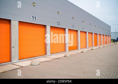 außen eine gewerbliche Lagerhalle mit orange Rolltore Stockfoto