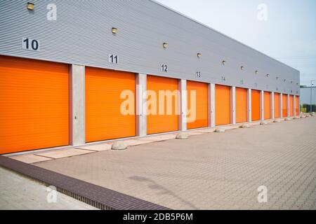 außen eine gewerbliche Lagerhalle mit orange Rolltore Stockfoto