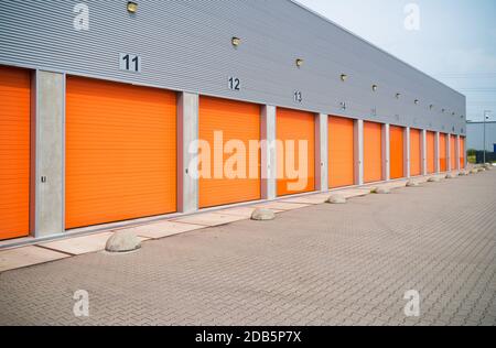außen eine gewerbliche Lagerhalle mit orange Rolltore Stockfoto