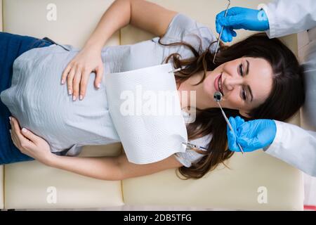 Ein männlicher Zahnarzt Behandlung der Zähne von jungen schwangeren Frau Patient in der Klinik Stockfoto