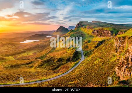 Lange kurvenreiche Straße bei Quiraing auf der Isle of Skye mit einem wunderschönen, lebhaften Sonnenaufgangshimmel. Stockfoto