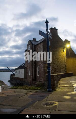 Graues Steinhaus auf schmalen Kiesel Straße biegen in schottischen Stadt auf den Orkney Inseln Stockfoto