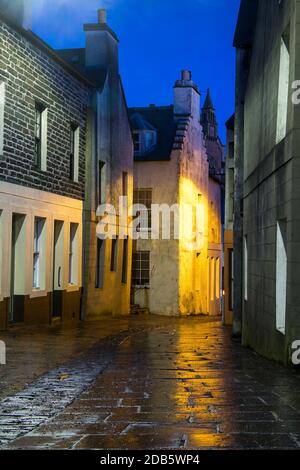 Schmale Straße in schottischer Stadt mit weißen Häusern und Licht Nachts Stockfoto