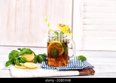 Das Glas Eistee auf Holztisch. Cuba Libre oder Long Island Cocktail, kaltes Getränk oder Limonade mit Zitrone und Basilikum. Stockfoto