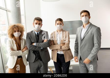 Gruppe von jungen Geschäftsleuten stehen im Büro und Tragen Sie Masken als Schutz vor Corona-Virus Stockfoto