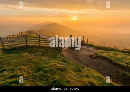 Goldener Sonnenaufgang am Mam Tor im English Peak District an einem trüben Herbstmorgen mit Holztor. Stockfoto