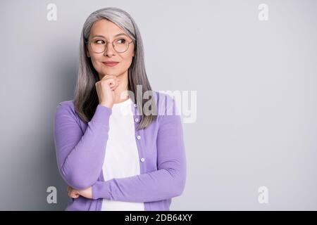 Portrait Foto von smart intelligente ältere Frau trägt Brillen suchen An der Seite denken über Idee berühren Gesicht isoliert auf grau Farbe Stockfoto