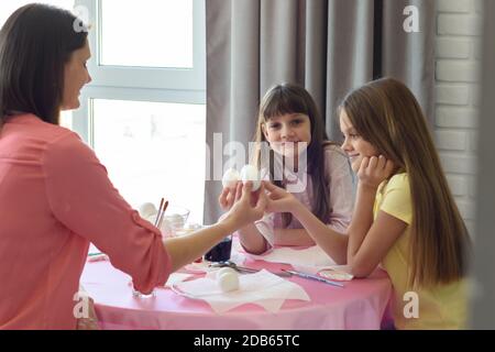 Tochter und Mutter halten Hühnereier, bevor sie anfangen, sie zu färben Stockfoto