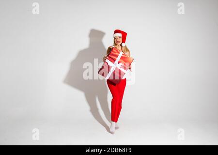 Hübsche Frau mit eingewickelten Weihnachtsgeschenk. Weihnachtsgeschenk in rotem Papier mit weißer Schleife verpackt.. Stockfoto