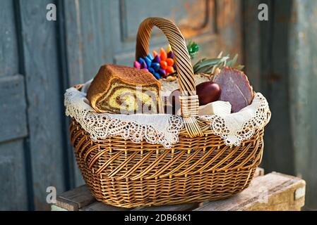 Traditionelle österliche Küche mit Schinken, Eiern und Brot. Urlaub im Freien. Der Osterkorb ist mit allerlei köstlichen Delikatessen gefüllt Stockfoto