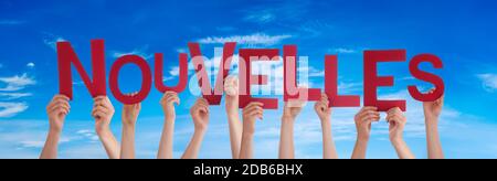 "People Hands Holding Bunt French Word Nouvelles Means News". Blauer Himmel Als Hintergrund Stockfoto