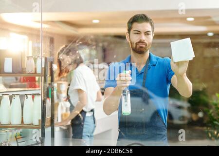 Der Besitzer des Coffeeshops putzt Glaswände Stockfoto