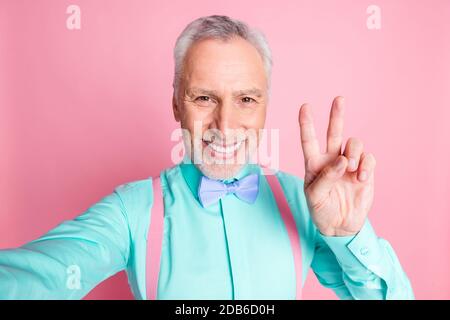 Nahaufnahme Foto Porträt von Senior Gentleman Blick auf die Kamera Aufnahme Selfie tragen zeigt V-Zeichen isoliert auf rosa Hintergrund Stockfoto