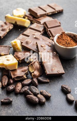 Milchschokoladenriegel. Dunkle und weiße Nussschokolade mit Kakaopulver und Kakaobohnen. Stockfoto