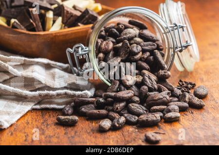 Kakaobohnen im Glas auf Holztisch. Kakaobst auf Holzgrund. Stockfoto