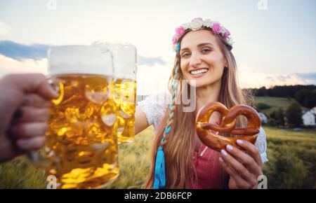 POV-Aufnahme von Paar in Bayern in traditioneller Kleidung Toasting mit Bier Stockfoto